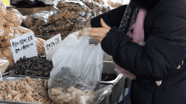 A person selecting traditional snacks at a market