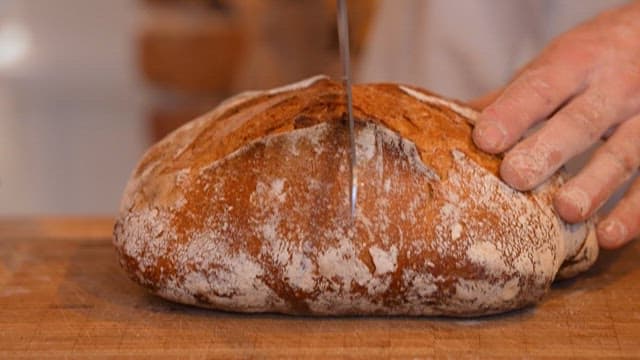 Person cutting rye bread with a knife