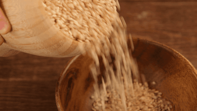 Grains being poured into a wooden bowl
