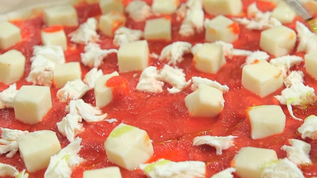 Olive oil sprinkled on pizza dough topped with tomato sauce and cheese