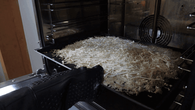Hand putting enoki mushrooms into oven