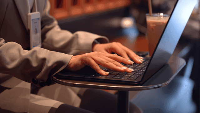 Female office worker typing on laptop at cafe