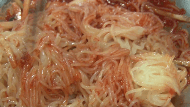 Spicy wheat noodles being mixed in a bowl
