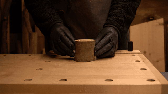 장갑을 낀 손이 나무 조각을 다루는 모습