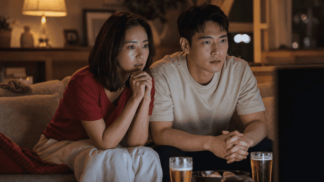 Couple intently watching TV and drinking beer