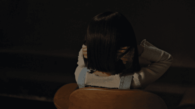 실내에서 의자에 앉아 있는 귀를 막은 아이