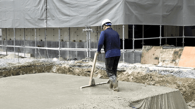 건설 현장에서 콘크리트를 고르는 작업자