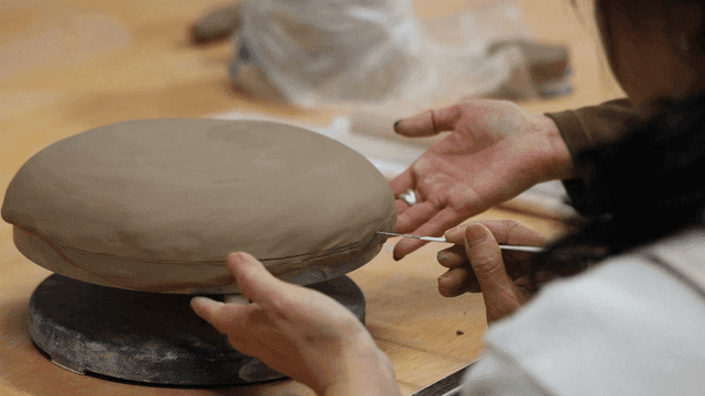 Person who teaches child how to make intricate pottery