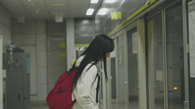 Young woman waiting in front of subway screen doors