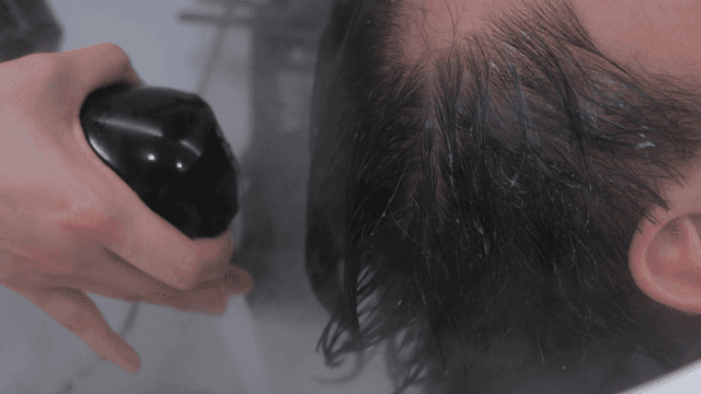 Hairdresser washing hair with hand shower