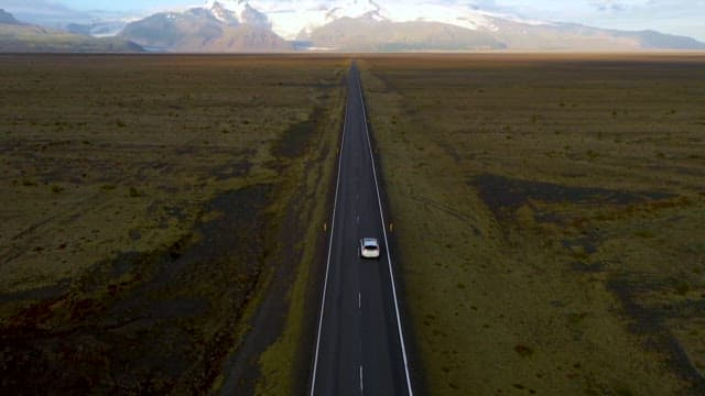 광활한 평원에 펼쳐진 일자 도로를 달리는 자동차