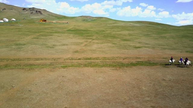 Riders on horses in a vast open field