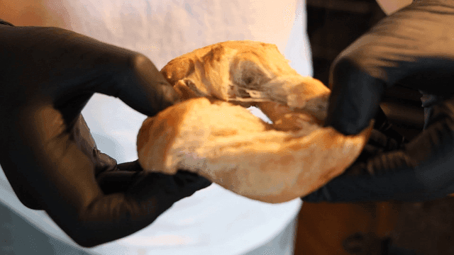 장갑을 낀 빵을 찢는 손