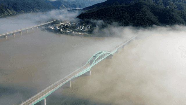 Bridge over foggy river and mountains