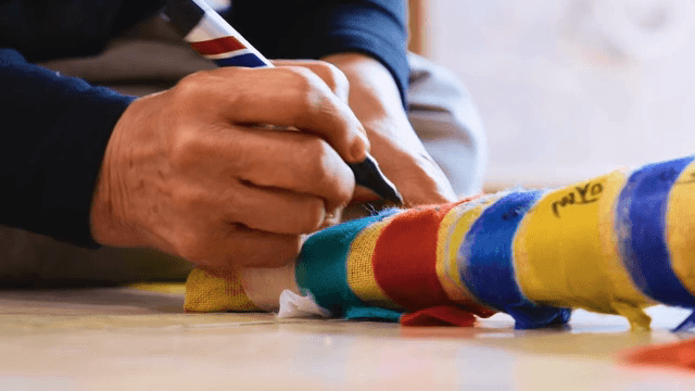 Person writing on five-colored cloth