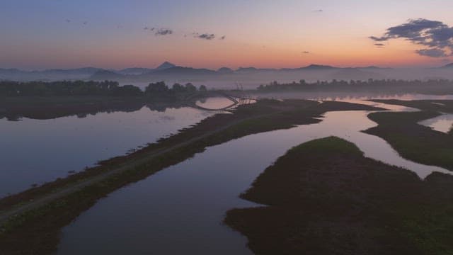 Serene river with misty mountain at sunset