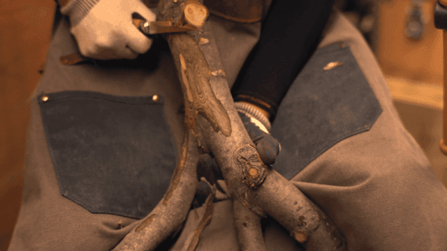 실내에서 나무를 칼로 깎는 사람