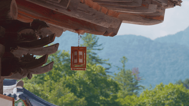 Lantern hanging from hanok eaves with distant mountain view