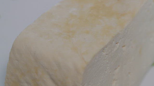 Close-up of tofu being pressed by a finger