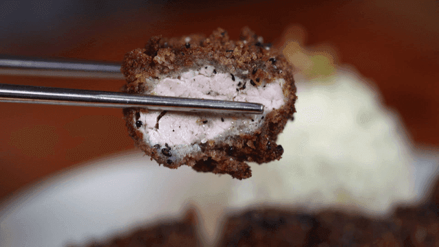 Crispy black pork cutlet picked up with chopsticks