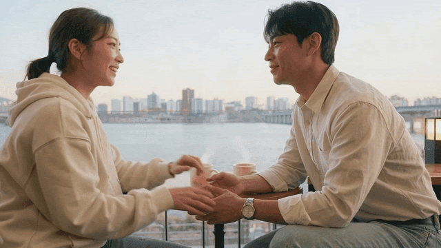 Couple holding hands and enjoying warm coffee by river