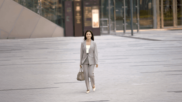 A woman in a suit walking in a city plaza