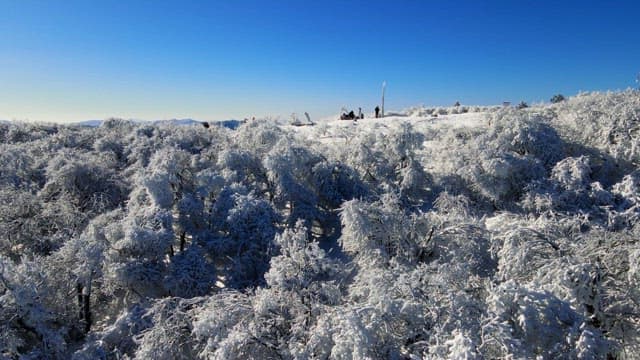 People enjoying the magnificent view of the mountain range from the top of a snow-covered mountain