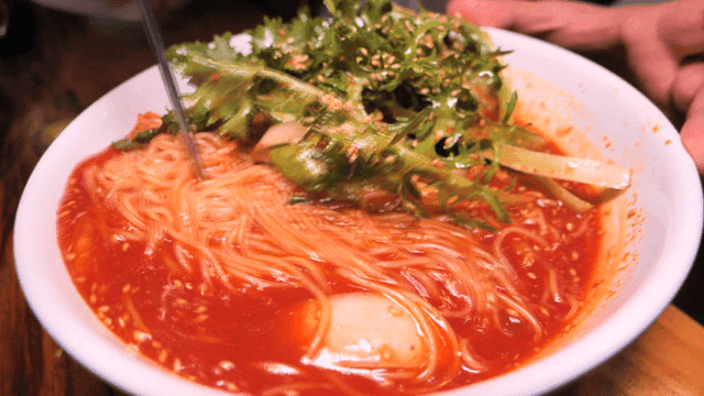 Chopsticks mixing spicy bibim guksu in bowl