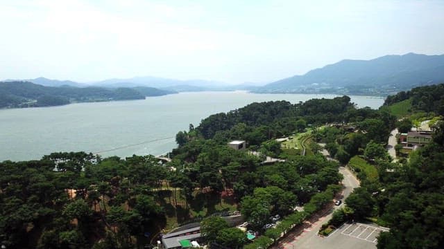 View of a lakeside area with lush greenery and distant mountains in daylight