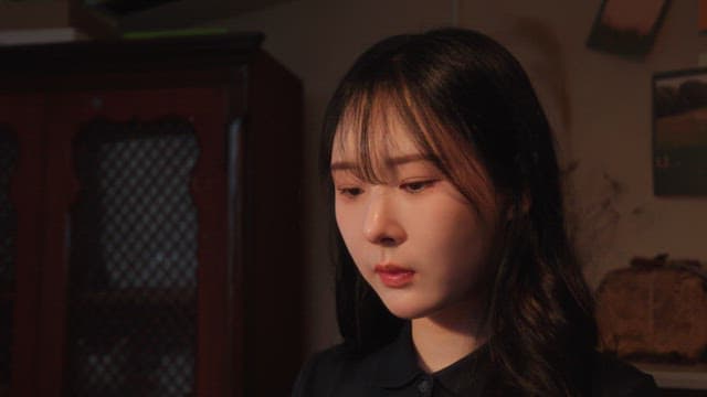 생각에 잠긴 표정으로 실내에 앉아 있는 여성