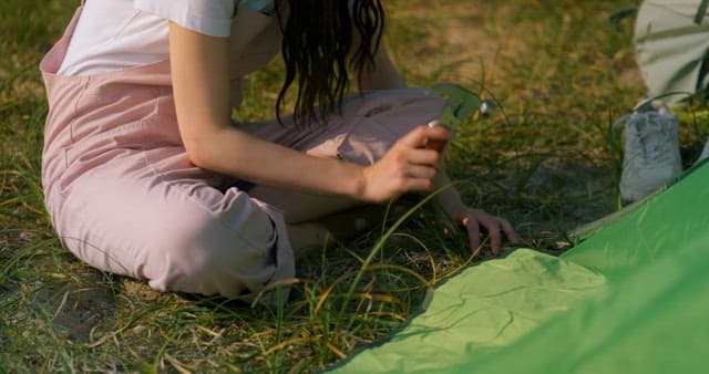 Woman Setting Up a Tent on the Grass