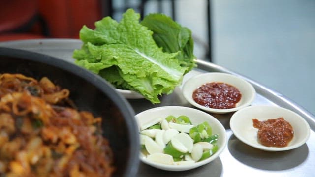 Stir-fried gopchang with vegetables cooked on an hot plate on a restaurant table