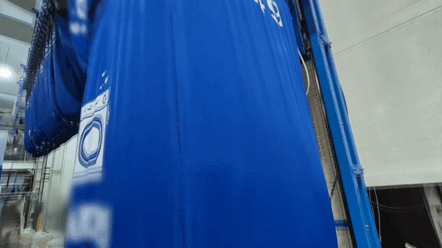 Laundry factory machine lifting piles of white fabric