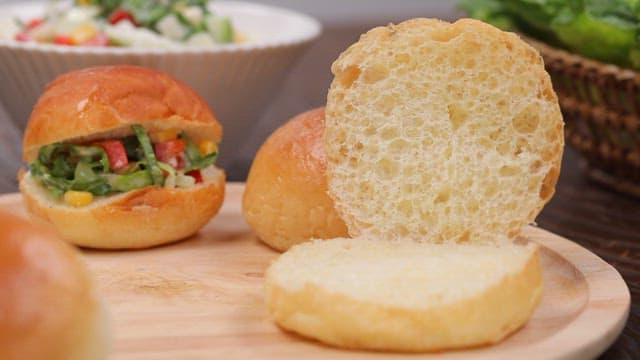 숟가락으로 신선한 코울슬로를 빵에 얹어 샌드위치를 만드는 모습