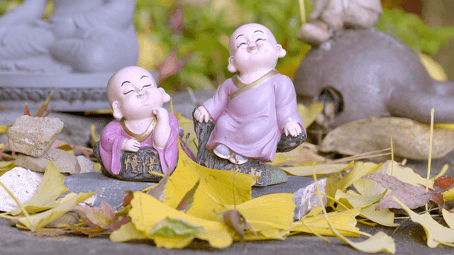 Two monk statues among fallen leaves
