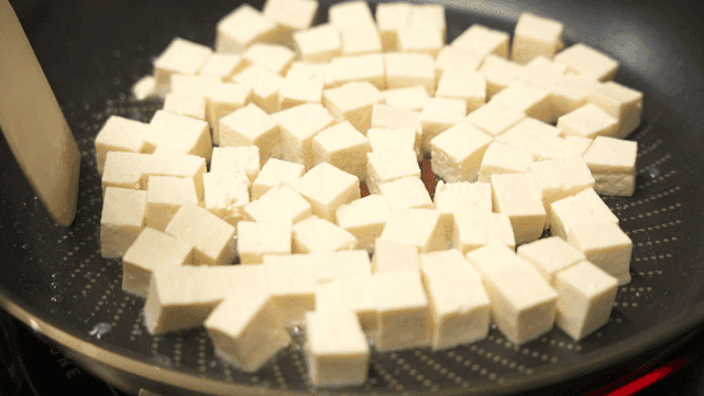 Tofu cubes being cooked in a pan