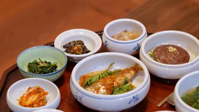 Traditional Wooden Table being Set with Side Dishes Korean Meal