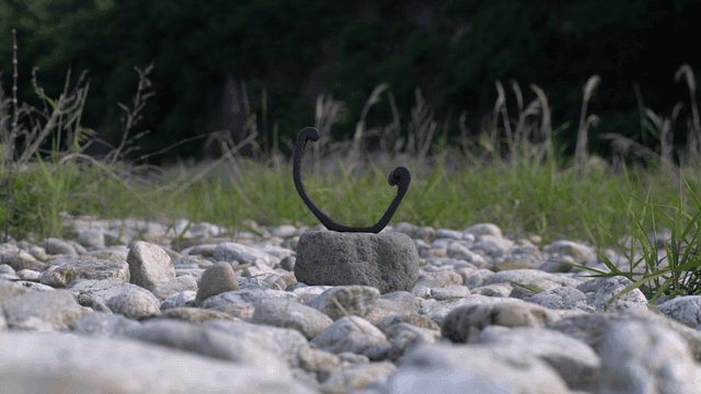 자갈밭 가운데 놓인 나무 조각품