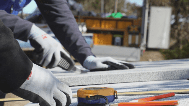 Worker cutting insulation material outdoors