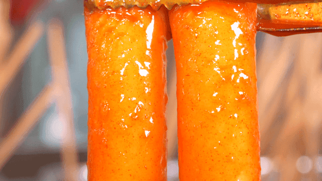 Spicy rice cakes dripping with broth when picked up with tongs