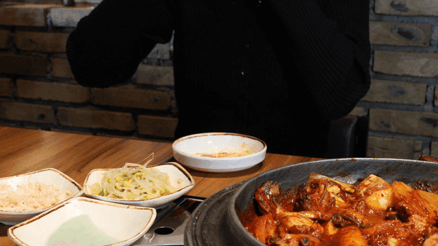 Person eating spicy Korean chicken jjagalbi with salad at restaurant