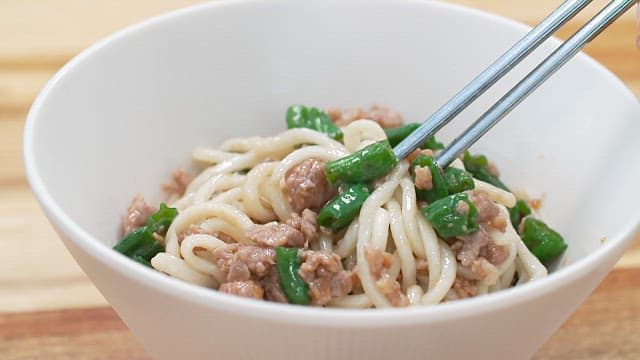 Chopsticks of delicious noodles with diced meat and chili peppers