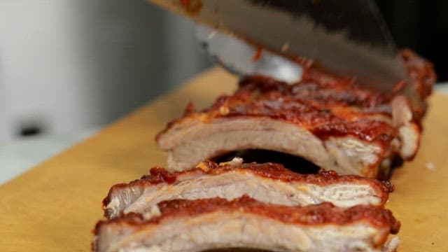 Slicing barbecued ribs on a cutting board