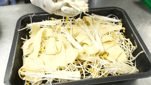 Tray topped with bean sprouts, dried tofu, and enoki mushrooms