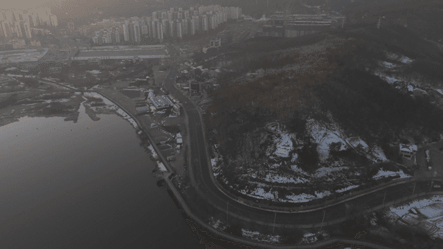 Cityscape with river and snow-covered hills.