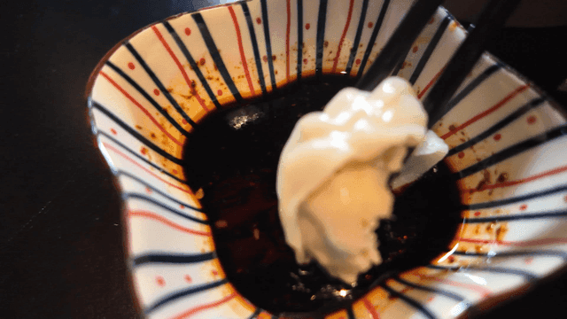 Chopsticks dipping dim sum into soy sauce