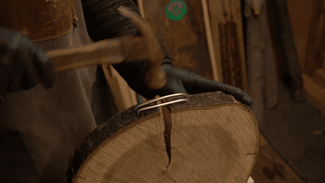 Craftsman hammering fixed wires into a log board