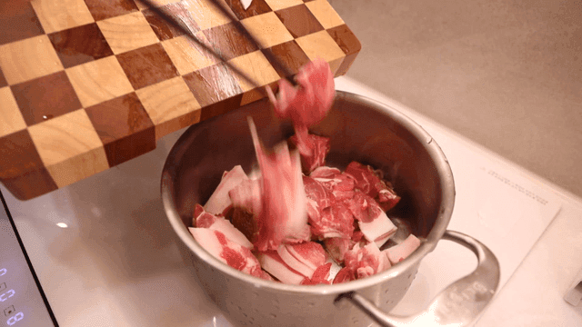 썰어진 돼지고기를 냄비에 넣는 장면