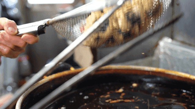 Person who takes fried seaweed rolls out and shakes off oil