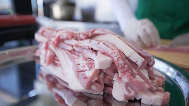 Chef preparing slabs of fresh pork in a clean kitchen